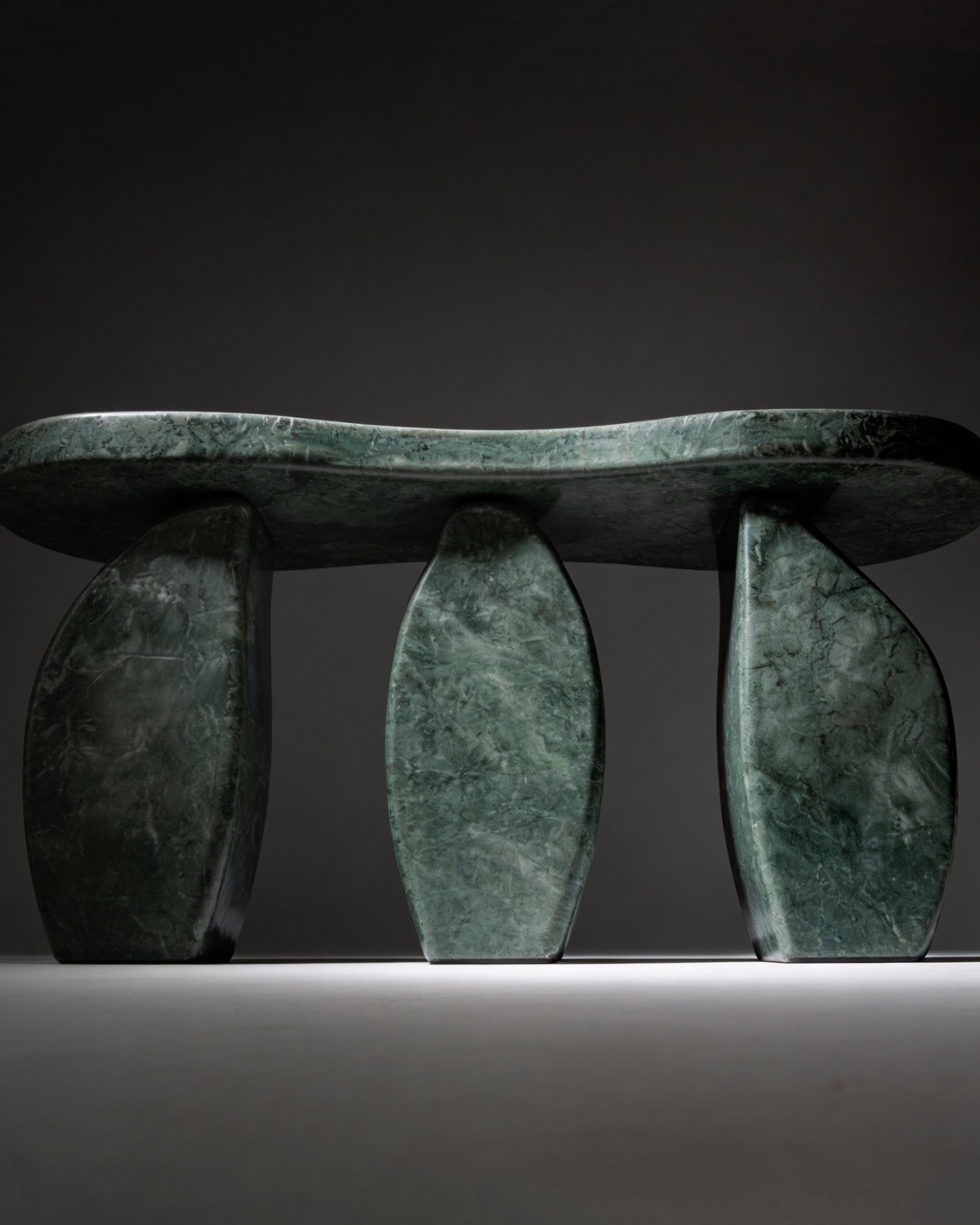 Verde Alpi serpentine marble table — a forest-green sculpture on three carved legs
